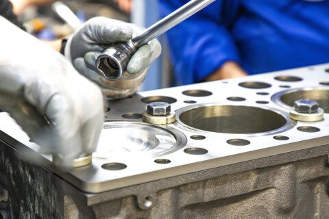 Працівник використовує ключ для затягування елементів двигуна.