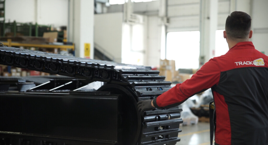 Працівник перевіряє систему гусеничного ходу в виробничому цеху.