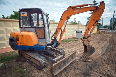 Фотографія, на якій зображено невеликий екскаватор марки Hitachi, припаркований на будівельному майданчику.