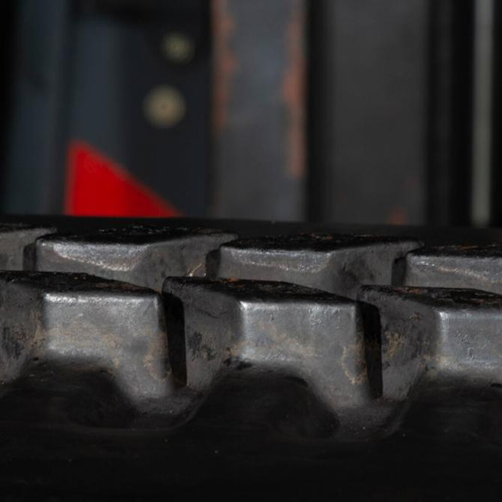 Збільшене зображення гумової гусениці будівельної машини, на якому видно деталі протектора.