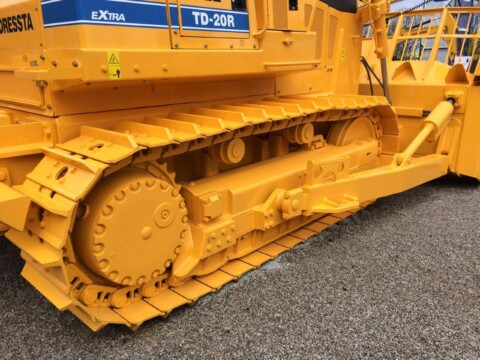 Жовта гусенична ходова частина від будівельної машини типу бульдозера.