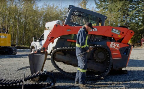 Технік, який ремонтує гусеничну ходову частину машини Kubota SVL 95-2s.