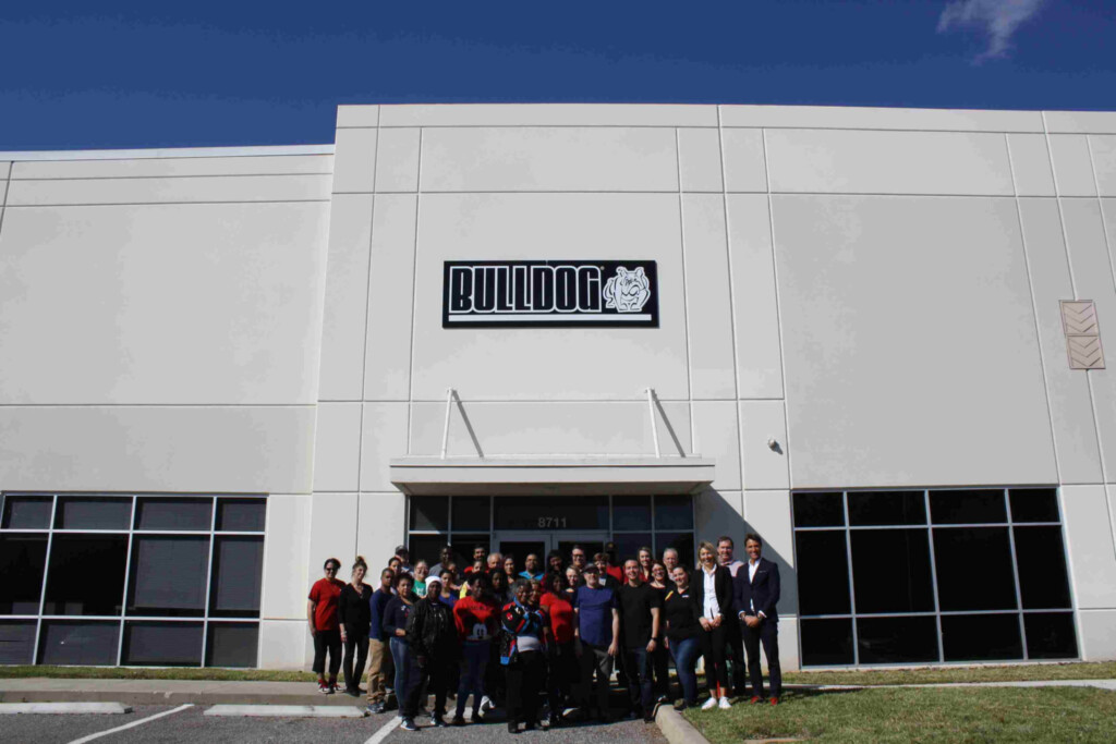 Група людей стоїть перед будівлею з логотипом BULLDOG.