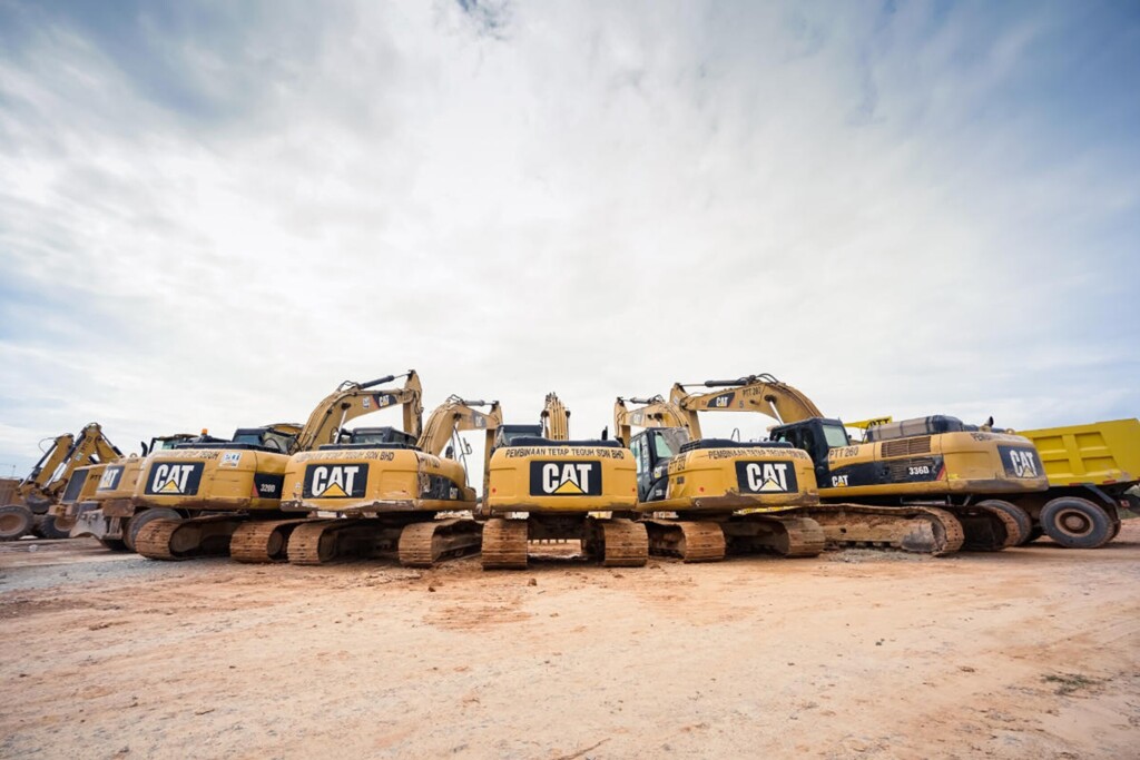 Ряд жовтих екскаваторів марки Caterpillar, встановлених на будівельному майданчику.