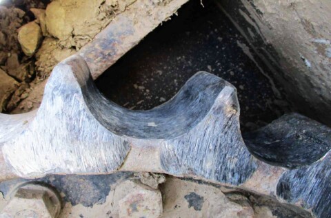 Збільшене зображення зношеного приводу в ходовій частині будівельної техніки.