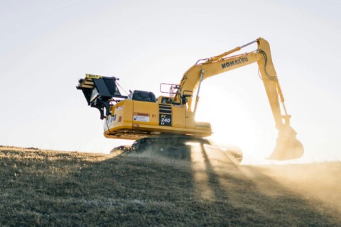 Екскаватор Komatsu PC240 LC працює на пагорбі на сході сонця.