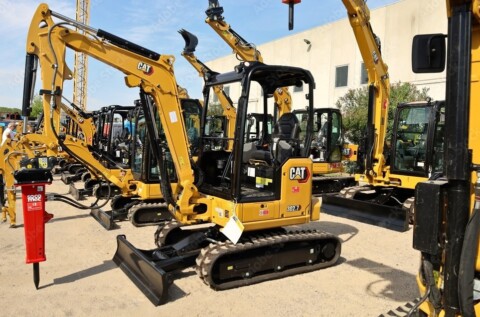 Кілька міні-екскаваторів CAT вишикувалися в лінію.