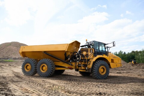 Жовтий будівельний тягач стоїть на будівельному майданчику, а на задньому плані - пагорб землі.