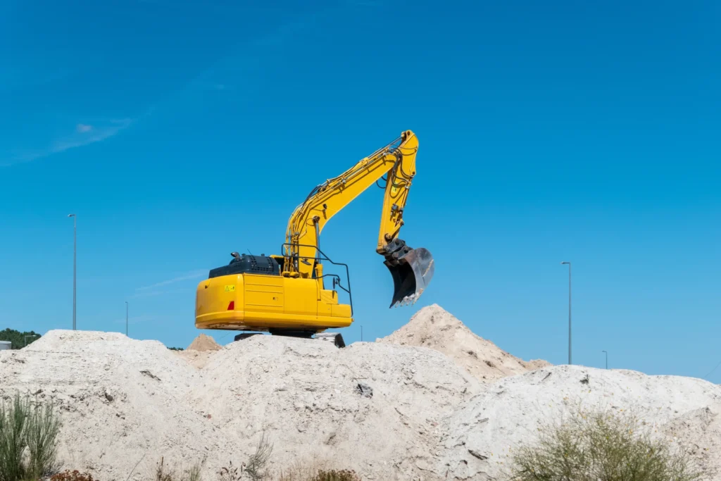 Гусеничний екскаватор працює на купі піску під час земляних робіт