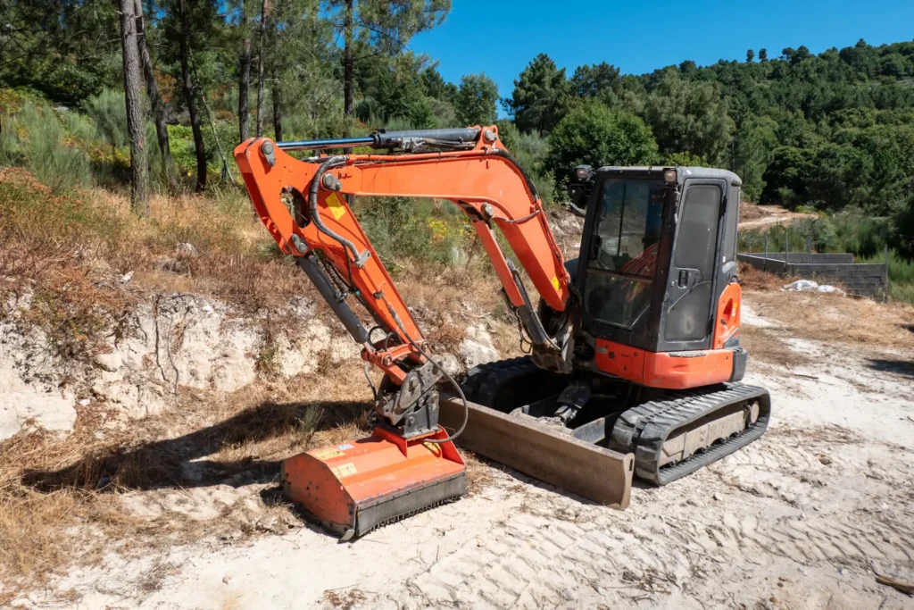 Міні-екскаватор працює в лісовій місцевості під час земляних робіт