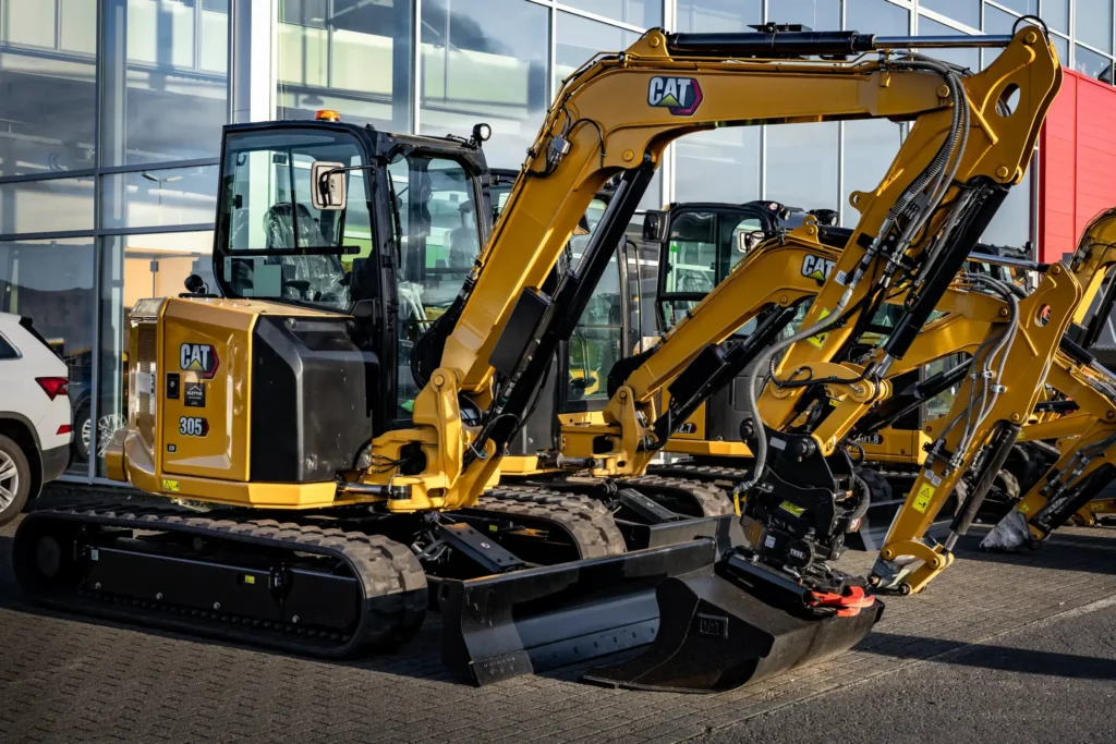 Гусеничний міні-екскаватор вагою приблизно 3 тонни, припаркований перед сервісним залом, готовий до земляних робіт