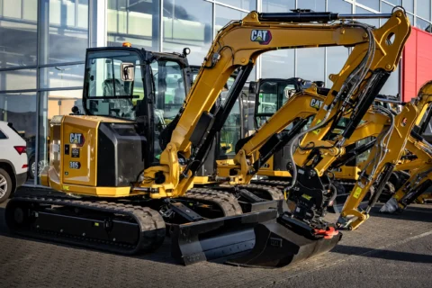 Гусеничний міні-екскаватор вагою приблизно 3 тонни, припаркований перед сервісним залом, готовий до земляних робіт