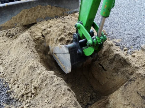 Міні-екскаватор проводить земляні роботи в піщаному ґрунті